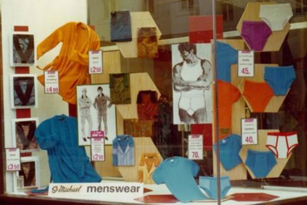 Colour image of a window display of brightly coloured menswear.