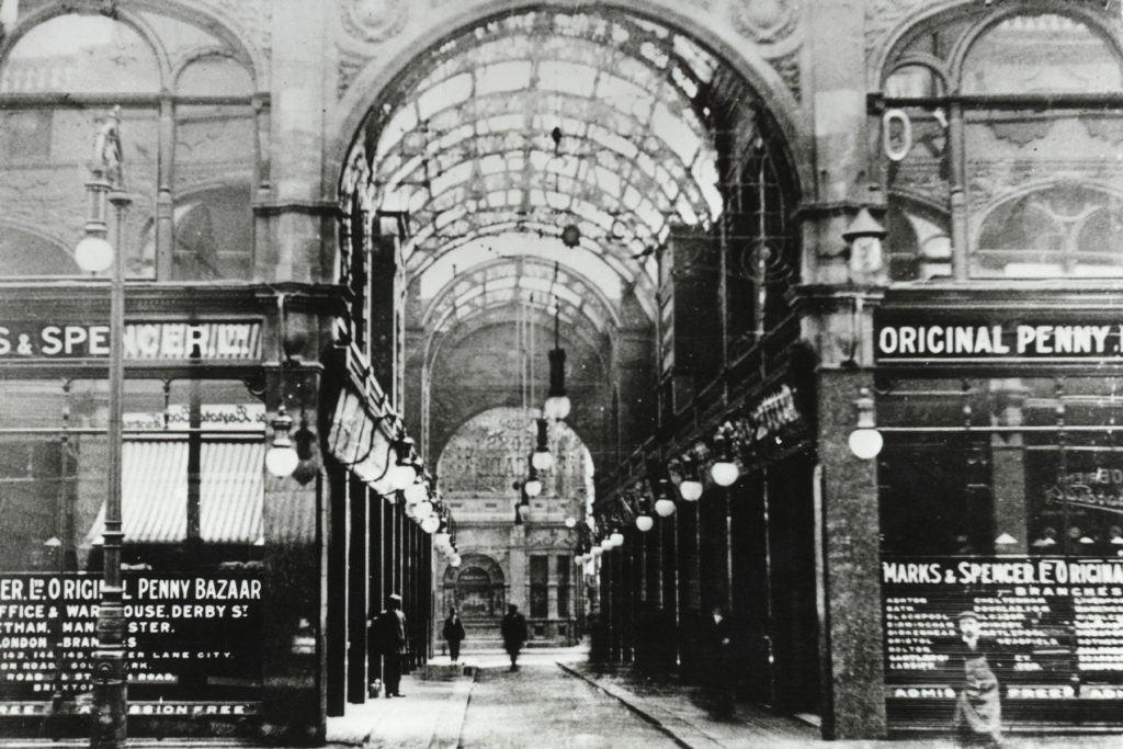 A black and white image of an arcade of shops.