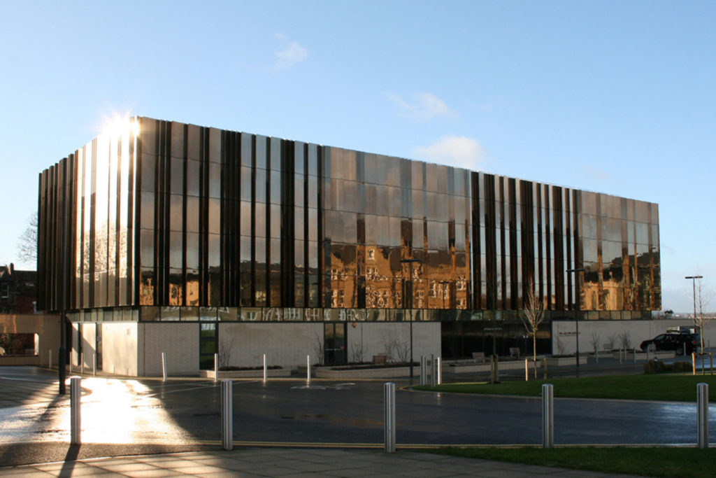 A colour image of a modern building with bronze cladding.