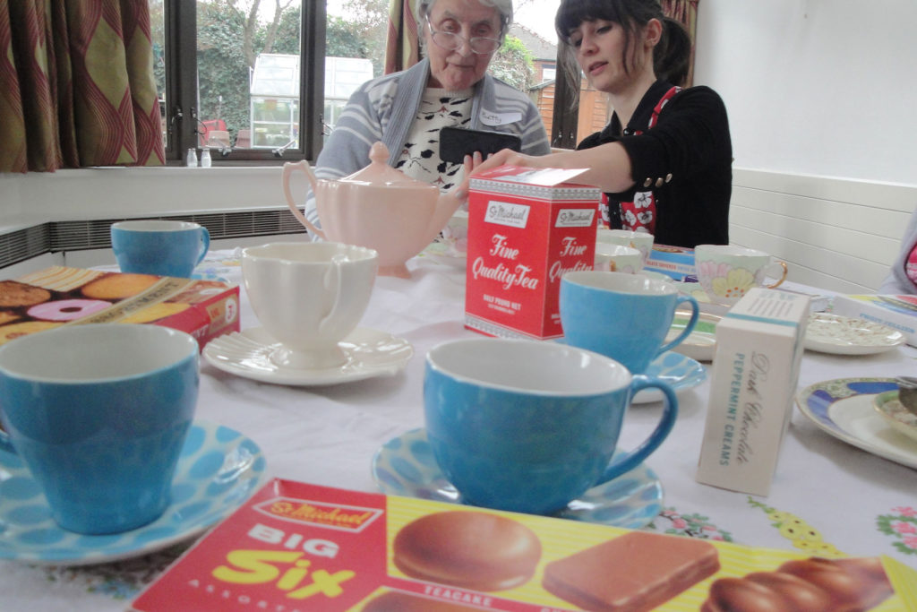 colour image of two people sitting a table set for tea