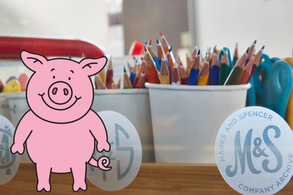 Colour image of pots of coloured pencils with an illustration of Percy Pig in front