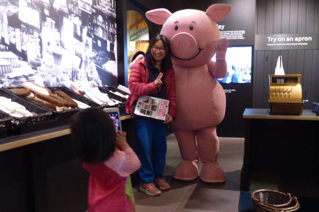 a colour image of a person having their photo taken with a life-size Percy Pig