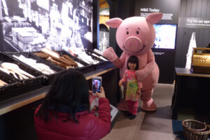 Colour image of a child taking a picture of her mum with Percy Pig