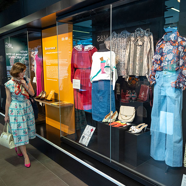 colour image of a person looking at museum displays of clothing