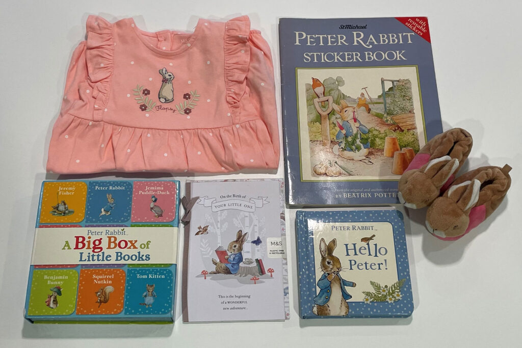A colour photo of a selection of books and children's clothing on a white table.