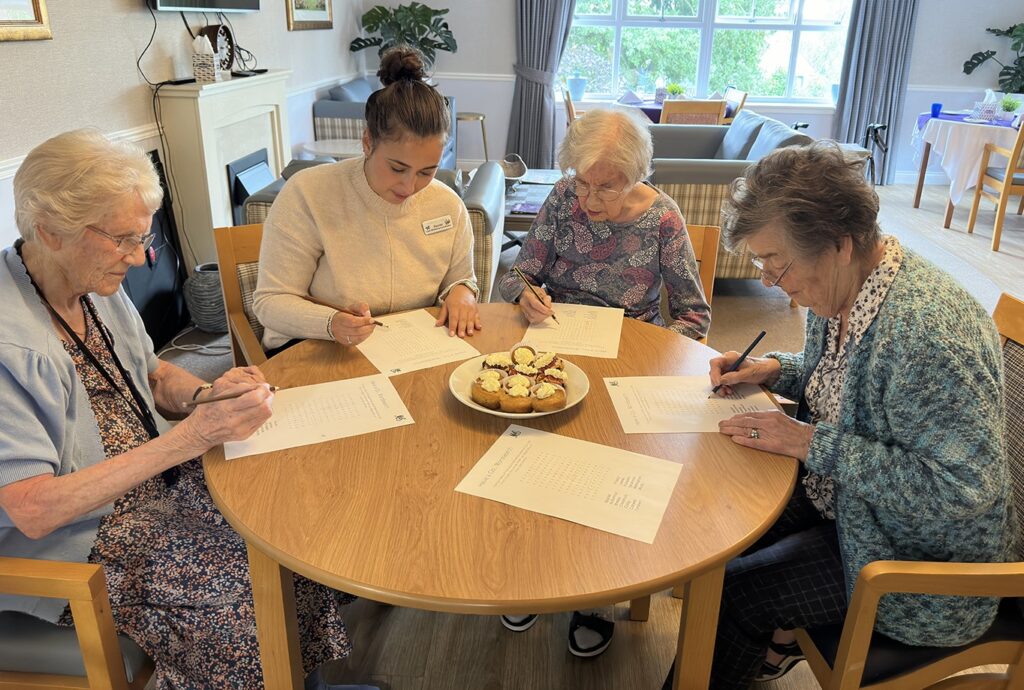 A group of people sit around a table, each holding a pencil and paper