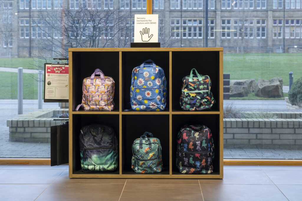 Colour photo of a shelf unit with colourful rucksacks.